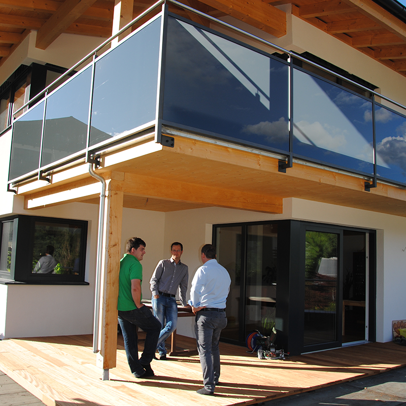 Personen die vor einem Vollholz Bau stehen und sich unterhalten