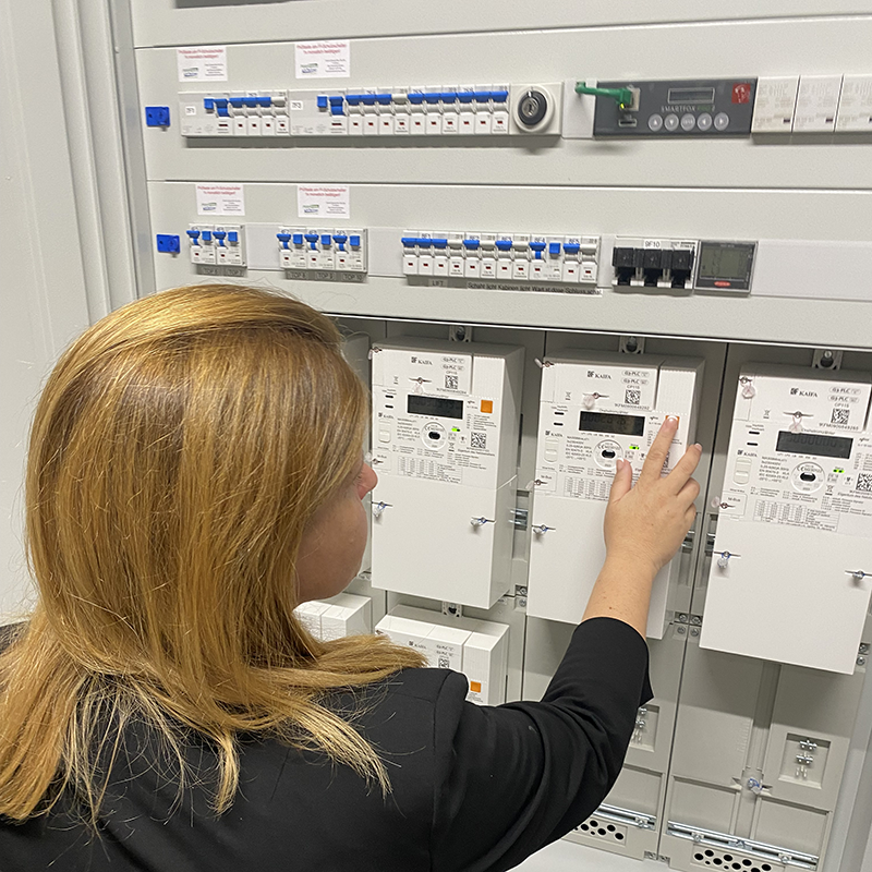 Mitarbeiterin blickt auf Stromzähler